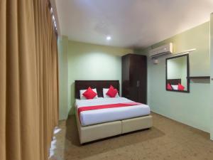 甘榜松盖拉马尔达兰Super OYO 1102 Amani Hotel的一间卧室配有一张带红色枕头和镜子的床