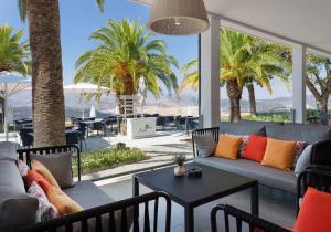 隆达雷纳维多利亚加泰罗尼亚酒店的客厅配有沙发和桌子,种植了棕榈树