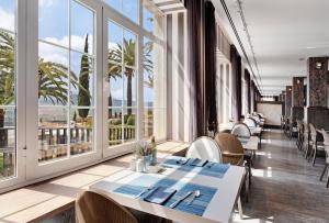 隆达雷纳维多利亚加泰罗尼亚酒店的餐厅设有桌椅和大窗户。