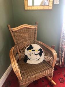 克利夫登Buttermilk Lodge Guest Accommodation的柳条摇椅上的奶牛枕头
