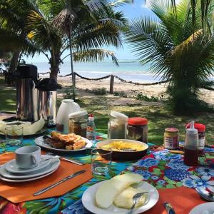 雅帕拉廷加Pousada Doze Cabanas的海滩上一张带食物盘的桌子