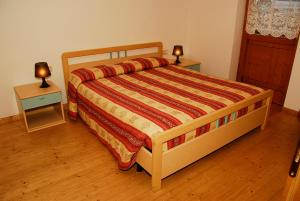 科戈洛Pejo Appartamenti Pegolotti的一间卧室配有一张带2个床头柜和2盏灯的床。