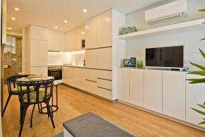 里斯本BmyGuest Bruno’s 36 Apartments的厨房配有白色橱柜、桌子和电视。