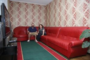 奥什MEDI Guest House的坐在红色沙发上的男人和女人