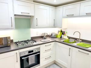 剑桥The Birches的厨房配有白色橱柜和炉灶烤箱。