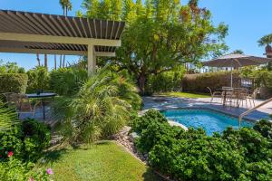 棕榈泉Desert Hills的后院设有游泳池、桌子和遮阳伞