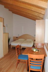 特伦托阿格例图维杜塔旅馆的卧室配有一张床和一张桌子及椅子