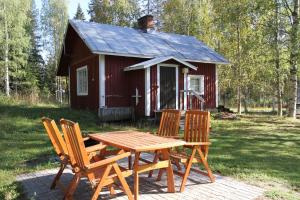 Ahmovaara科利欢乐时光小屋酒店的小屋前的野餐桌和椅子