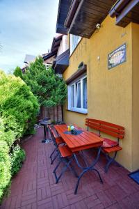 德兹维济诺Apartament Zuzia的砖砌庭院的红色野餐桌和长凳