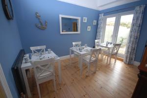 韦茅斯Weymouth Vegan B&B的一间拥有蓝色墙壁和白色桌椅的用餐室