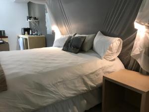 温特和克Bryan's View的卧室配有带枕头的白色床和电视。