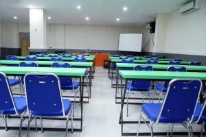 帕卢RedDoorz At Hotel Gajah Mada Palu的一间设有绿色桌子和蓝色椅子的教室