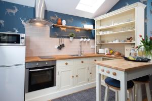 阿尼克Coach House B & B的厨房配有白色橱柜和蓝色的墙壁