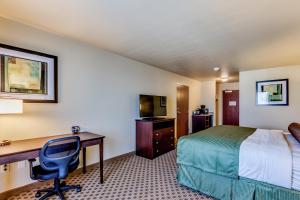 韦弗利Cobblestone Inn & Suites - Waverly的酒店客房设有一张桌子、一张床和一台电脑