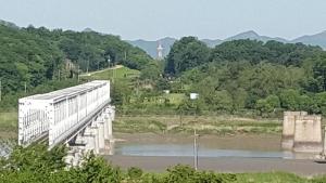 坡州市The Guesthouse DMZ Stay的一座桥,在河上,在远处有一个灯塔