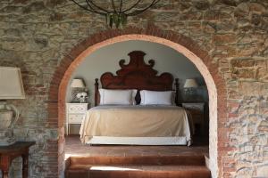 卡索莱德尔萨Castello di Casole, A Belmond Hotel, Tuscany的卧室配有砖墙内的床铺