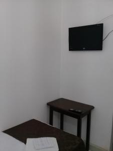 巴乌鲁Porto Seguro Office Hotel的一间设有桌子的房间和墙上的电视