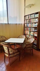 莱万托Ospitalia del Mare Hostel的一张桌子和两把椅子,书架上摆放着书籍