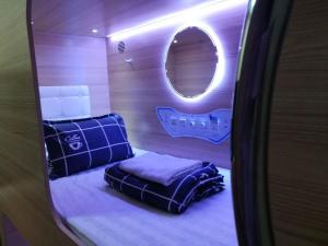 新加坡CapsulePod@Aljunied的小房间设有床和圆镜子