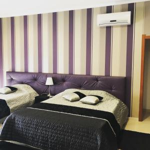 阿利若Alojamento Galerias Nascentes的一间卧室设有两张床和紫色床头板