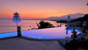 特鲁卡那拉特Princess of Mentigi Bay的日落时分享有海洋美景的游泳池