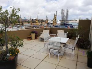 科斯皮夸Three Cities Apartments的一个带桌椅的庭院和一个海港