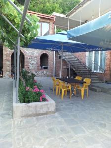 西格纳吉格鲁吉亚兹明达旅馆的庭院配有桌椅和蓝伞。