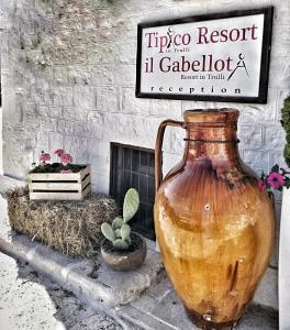 阿尔贝罗贝洛迪比科度假酒店的坐在标志前的大花瓶