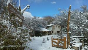 圣卡洛斯-德巴里洛切Hostel Los Coihues的雪覆盖的院子,有街道标志和房子