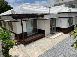 冲绳岛市Condominium WAFU TEI Okinawa city的白色的房子,带屋顶的门廊