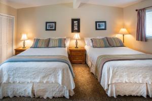 芬代尔红木套房酒店的配有两张床铺的房间,桌子上放着两盏灯