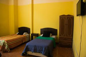 瓦尔帕莱索Hostal Tricontinental的黄色客房 - 带两张床和梳妆台