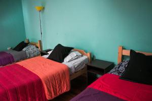 瓦尔帕莱索Hostal Tricontinental的一间设有两张红色毯子的床的房间