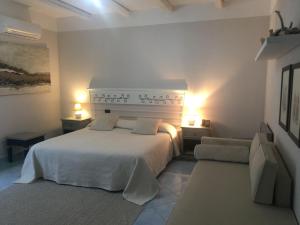 比蒂里苏酒店的卧室配有白色的床、两张桌子和两盏灯。