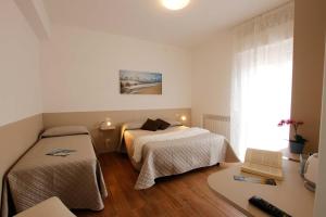 努马纳Affittacamere da Sabri的一间卧室设有两张床、一张桌子和一个窗口。