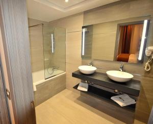 CheragaMADAURE HOTEL的一间带两个水槽和玻璃淋浴间的浴室