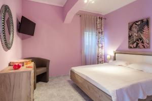 锡基亚family house nikos 2的卧室设有粉红色的墙壁、一张床和椅子
