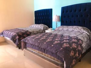 塔帕丘拉Santa Fe Hotel Boutique的一间卧室设有两张床和蓝色床头板