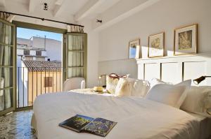 马略卡岛帕尔马Hotel Basilica的卧室配有一张白色的床,上面有书