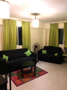 博卡奇卡热门公寓酒店的客厅配有两张黑色沙发和绿色窗帘