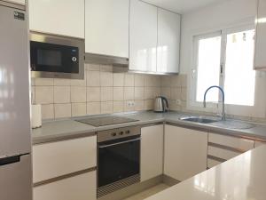 卡勒达德福斯特Sunny & New Apartamento in Caleta de Fuste的厨房配有白色橱柜、水槽和微波炉
