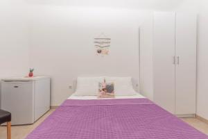 马卡尔斯卡Apartmani Sol的白色墙壁的客房内的紫色床