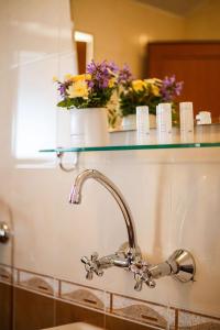 索佐波尔阿尔瓦特罗斯老城区酒店的浴室水槽,玻璃架上摆放着鲜花