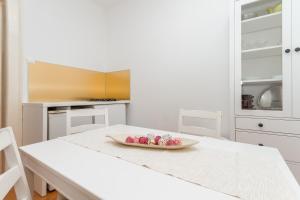 皮兰Apartment Petka的白色的厨房,配有桌子和一碗水果