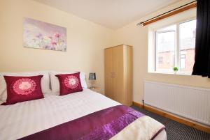 奥尔德姆No 10 LimeHouse的一间卧室配有一张带红色枕头的床和一扇窗户