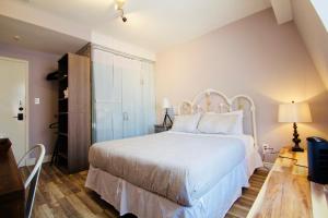 多伦多The Palmerston的卧室铺有木地板,配有白色的床。