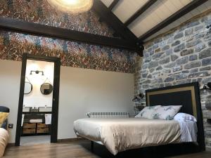 托尔拉Hostel-Albergue Monte Perdido的一间卧室设有一张床和石墙