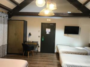 托尔拉Hostel-Albergue Monte Perdido的客房设有三张床、一张桌子和一台电视。