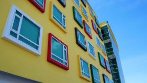 古晋松园酒店的黄色的建筑,上面有五颜六色的窗户