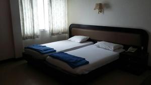 宋卡Queen Songkhla Hotel的一间卧室配有两张床和蓝色毛巾。